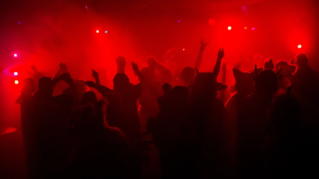 Crowd with hands up in red light at a late night party