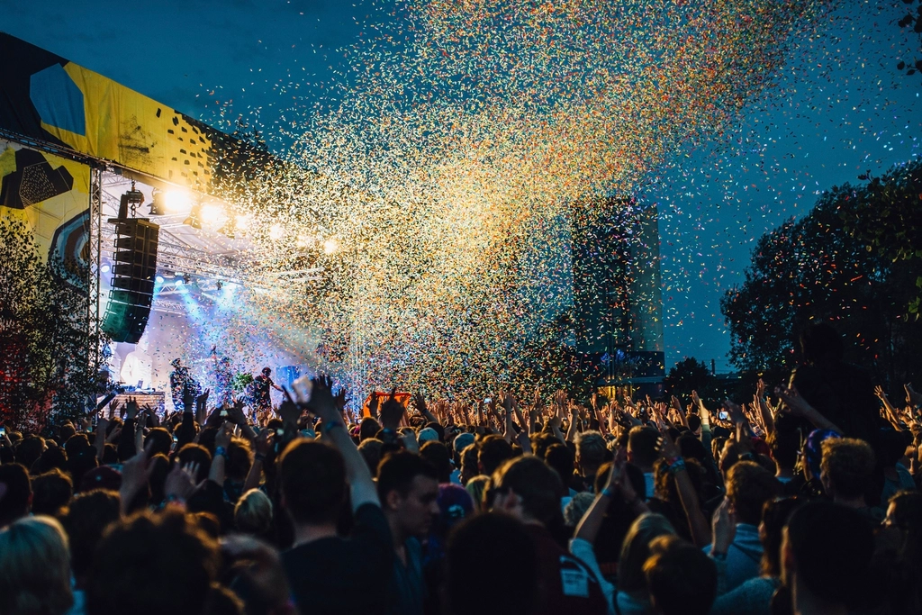 Confetti falling over a huge night crowd in front of a lit main stage